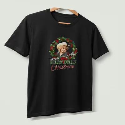Festive illustration of Dolly Parton with the text Have a HOLLY DOLLY Christmas in green, red, white, and gold — printed on a unisex t-shirt (angled view)