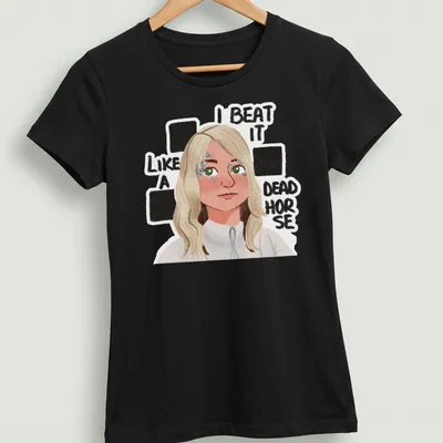 Cartoon figure with blonde hair and humorous text about beating a dead horse — printed on a women's shirt