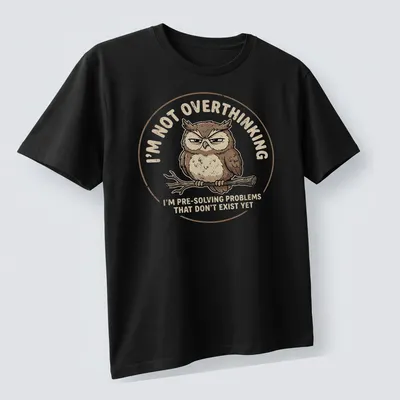 Cartoon owl design with humorous text about overthinking problems — printed on a unisex t-shirt (angled view)