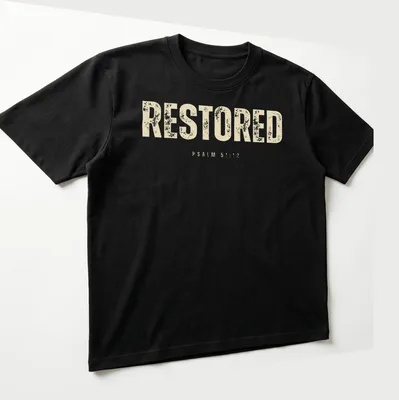 Bold distressed Christian shirt featuring the text RESTORED PSALM 51:12. — printed on a unisex t-shirt (angled view)