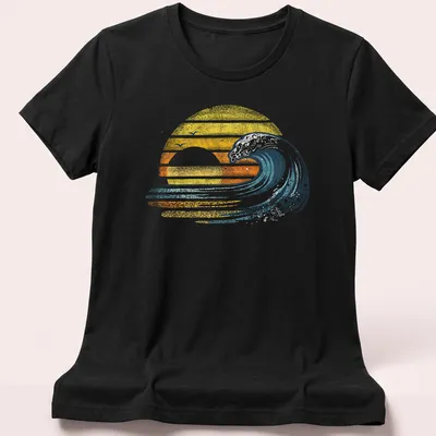 Retro distressed surfer tee featuring an ocean wave and sunset in yellow and orange — printed on a women's shirt