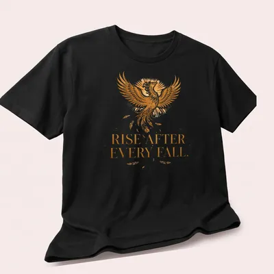 Detailed illustration of a phoenix with the text 'Rise After Every Fall' in gold and orange — printed on a unisex t-shirt (angled view)