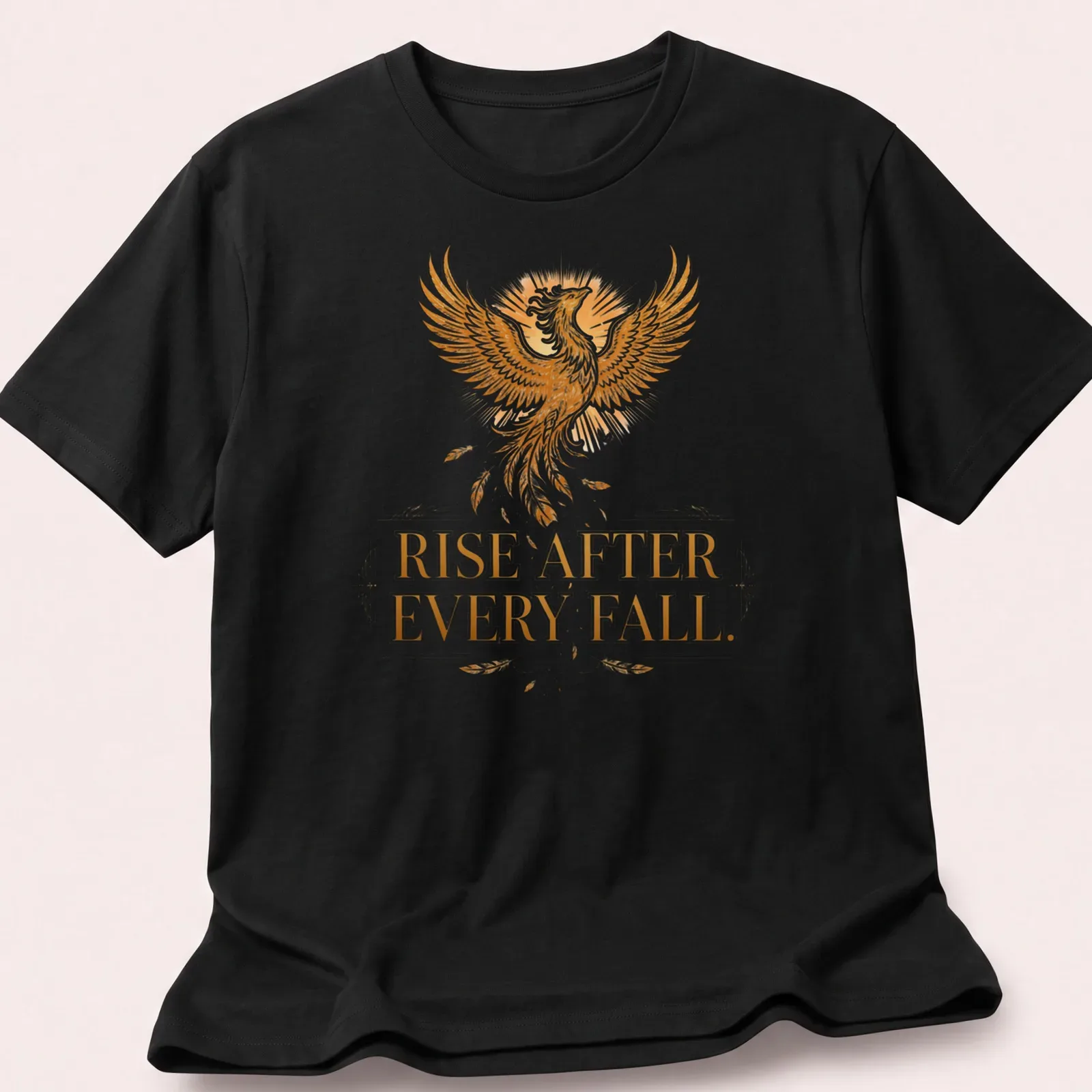 Detailed illustration of a phoenix with the text 'Rise After Every Fall' in gold and orange — printed on a unisex t-shirt
