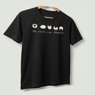 Minimalist sheep illustration with the text 'the Lord is my Shepherd' in cream and black. — printed on a unisex t-shirt (angled view)