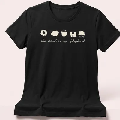 Minimalist sheep illustration with the text 'the Lord is my Shepherd' in cream and black. — printed on a women's shirt