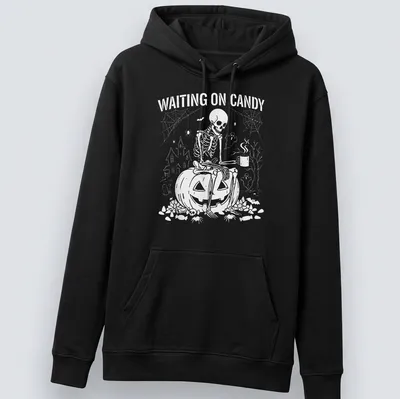 Spooky illustration of a skeleton on a pumpkin with text saying 'Waiting on Candy' — printed on a unisex hoodie