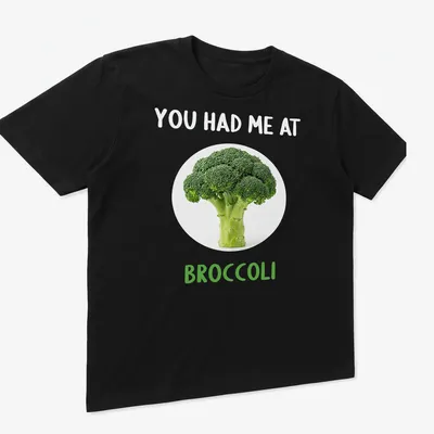 Funny broccoli-themed shirt with playful text in green and white — printed on a unisex t-shirt (angled view)